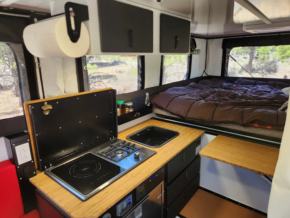 Hudson Bay 8 flatbed pop-up interior galley with induction cooktop, sink, and bamboo counter, with the bed area behind