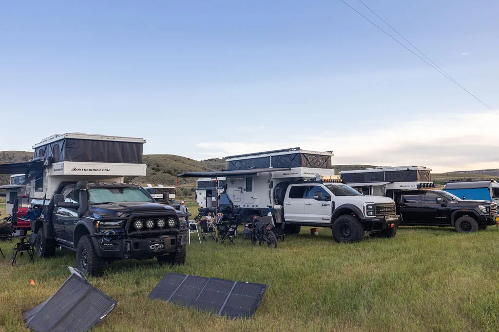 OEV pop-up truck campers set up at camp with portable solar panels laid out on the grass at The Big Thing 2026 in Three Forks, Montana