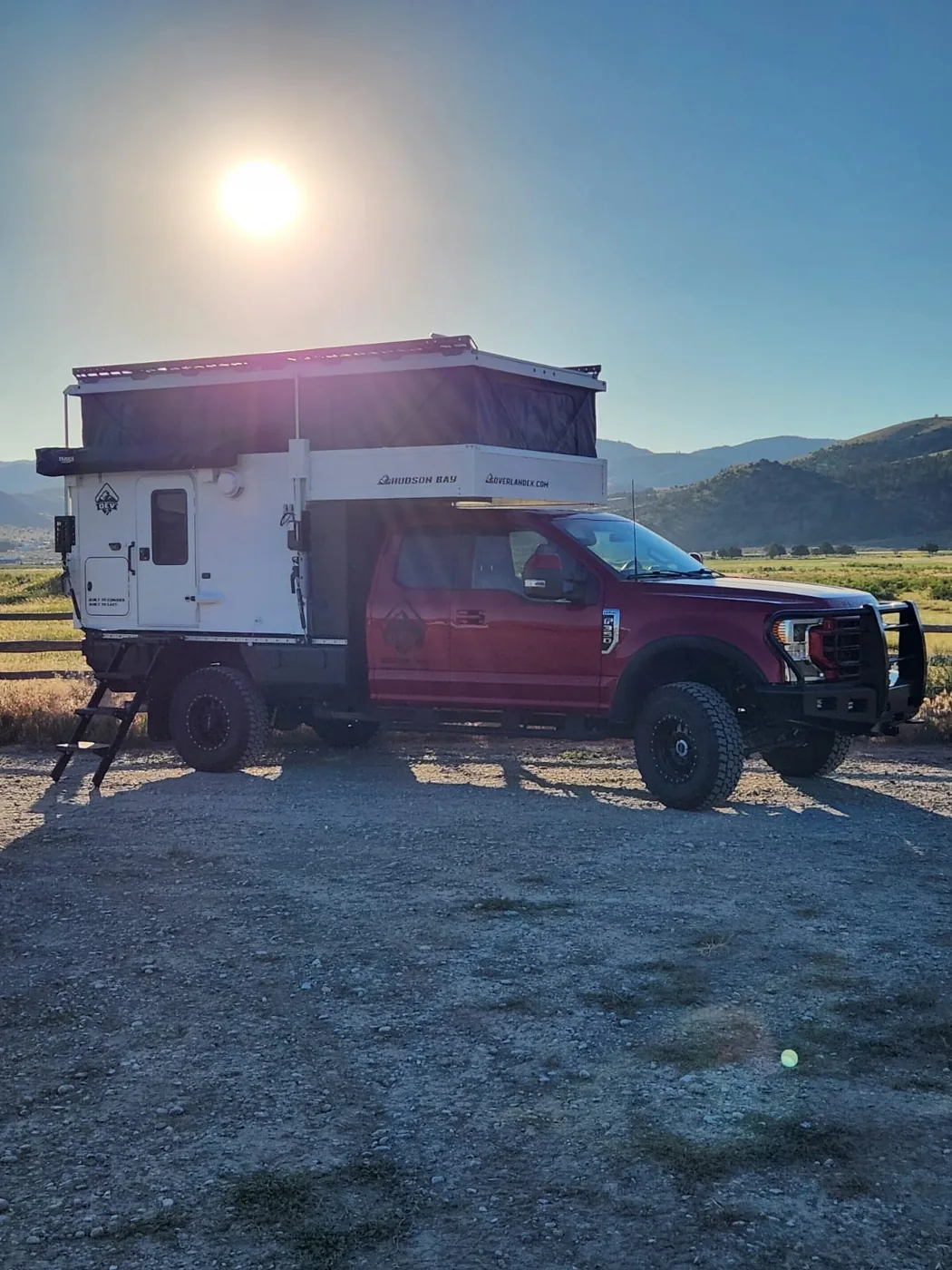 OEV Hudson Bay flatbed pop-up truck camper on a Ford Super Duty with mountains behind near Three Forks, Montana